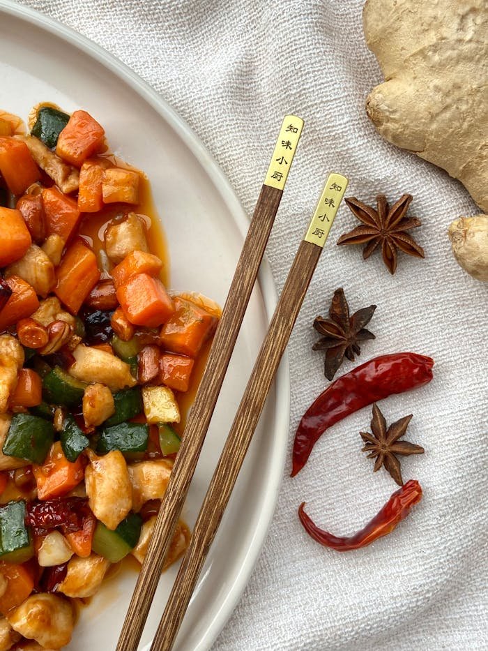 Top view of a colorful Asian stir-fried dish with spices and chopsticks, showcasing vibrant ingredients and flavors.